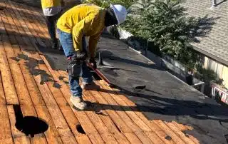 Workers repairing wooden roof with tools.