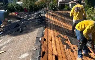 Workers repairing damaged wooden roof.