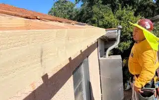 Construction worker on ladder inspecting roof