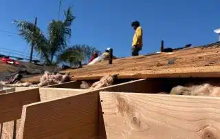 Construction workers repairing roof under clear sky.