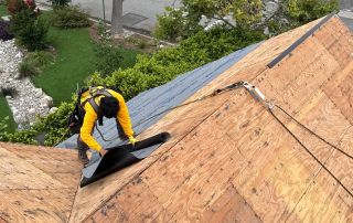 Person working on roof installation with safety gear.