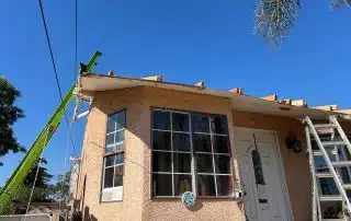 House roof under construction with ladder and crane.