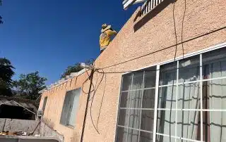 Person working on house roof under clear sky.