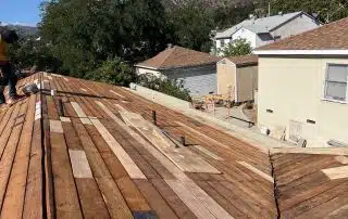 Construction worker builds wooden roof on house