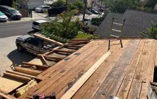 Rooftop construction with tools and truck in driveway.