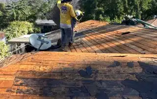 Worker repairing roof under blue sky.