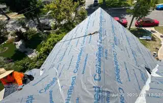 Worker installing CertainTeed roofing underlayment on house