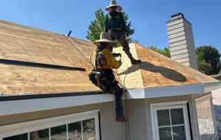 Workers repairing house roof under blue sky.