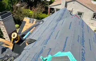 Roof under construction with worker and equipment.