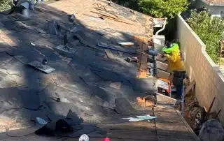 Roofers repairing shingles under blue sky, sunny day.