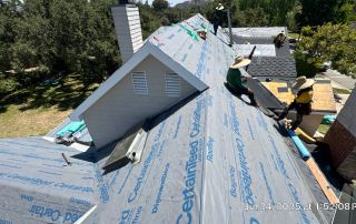 Workers installing roof shingles on residential rooftop.