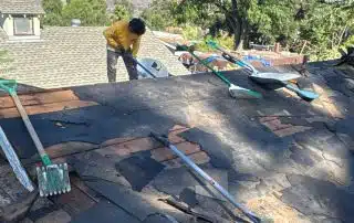 Man repairing roof under clear blue sky.