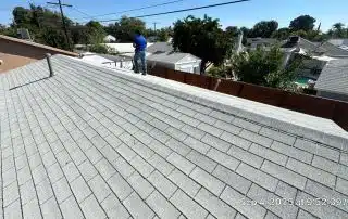 Person inspecting rooftop with gray shingles