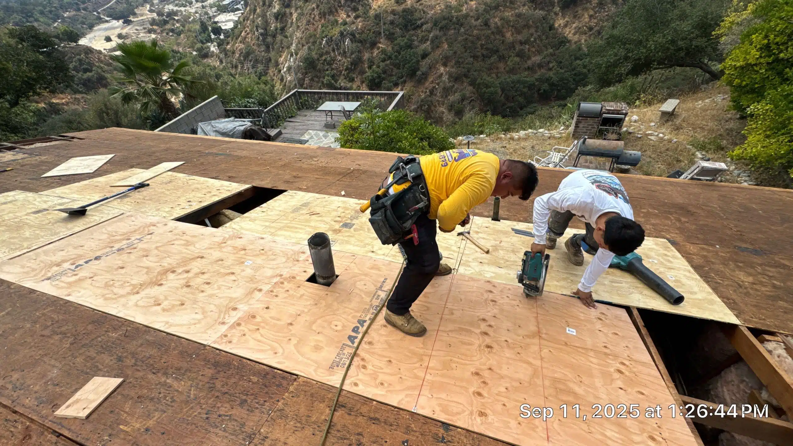 1-Sep 11 2025 01_26pm-ynFa Workers repairing roof with plywood in mountainous area.