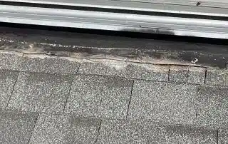 Damaged roof shingles near metal flashing.
