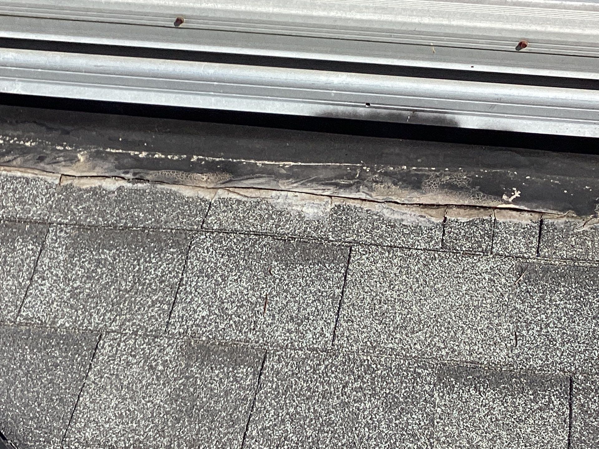 Damaged roof shingles near metal flashing.