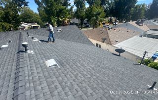 Man inspecting rooftop shingles on sunny day.