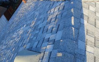 Worker inspecting shingled roof of residential home.