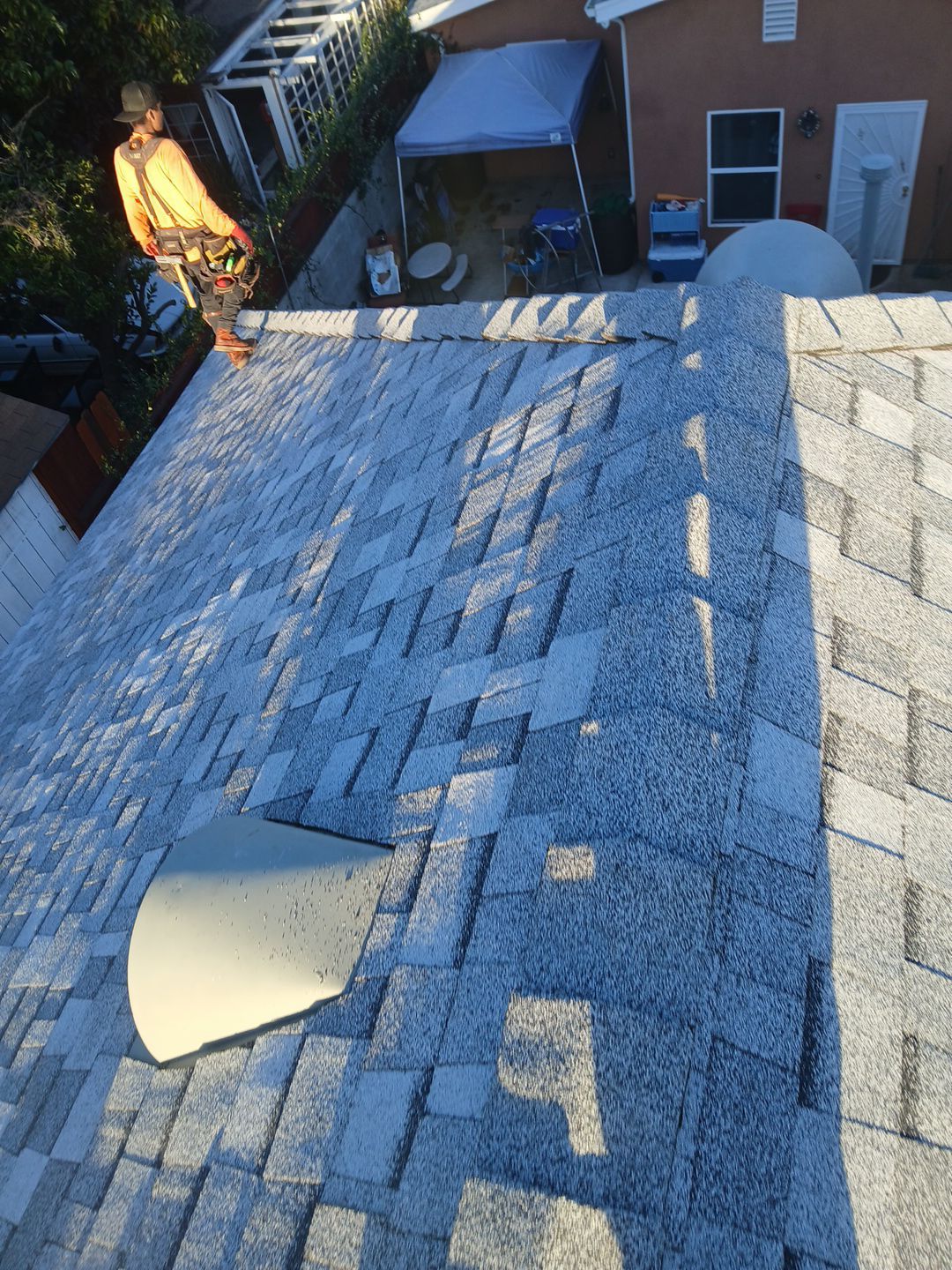 Worker inspecting shingled roof of residential home.
