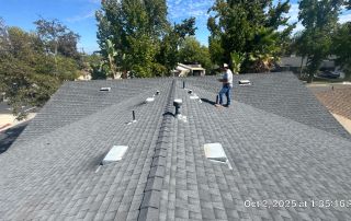 Worker inspecting gray shingle roof in residential area