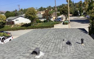Rooftop with vents overlooking suburban street scene.