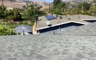 Rooftops with solar panels and distant hills view.