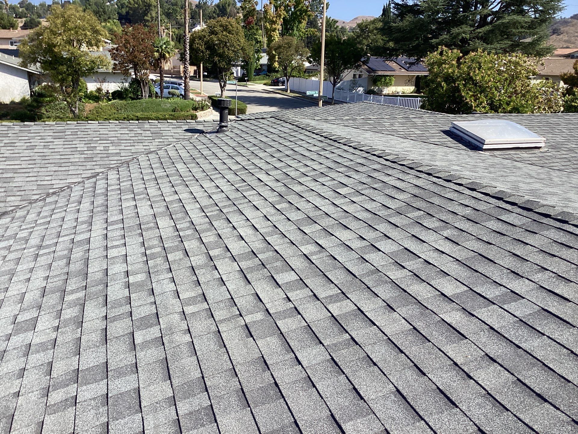 Asphalt shingle roof with skylight in suburban area.