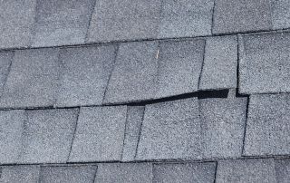 Gray asphalt roof shingles with slight damage.