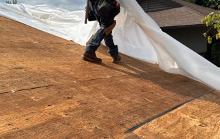 7-Sep 11 2025 02_40pm-TmYX Worker securing tarp on house roof