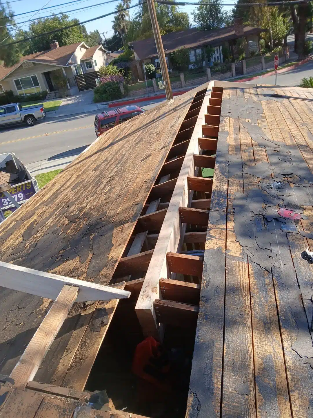 Roof under repair with nearby houses visible.