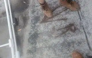 Person in work boots standing on rooftop surface.