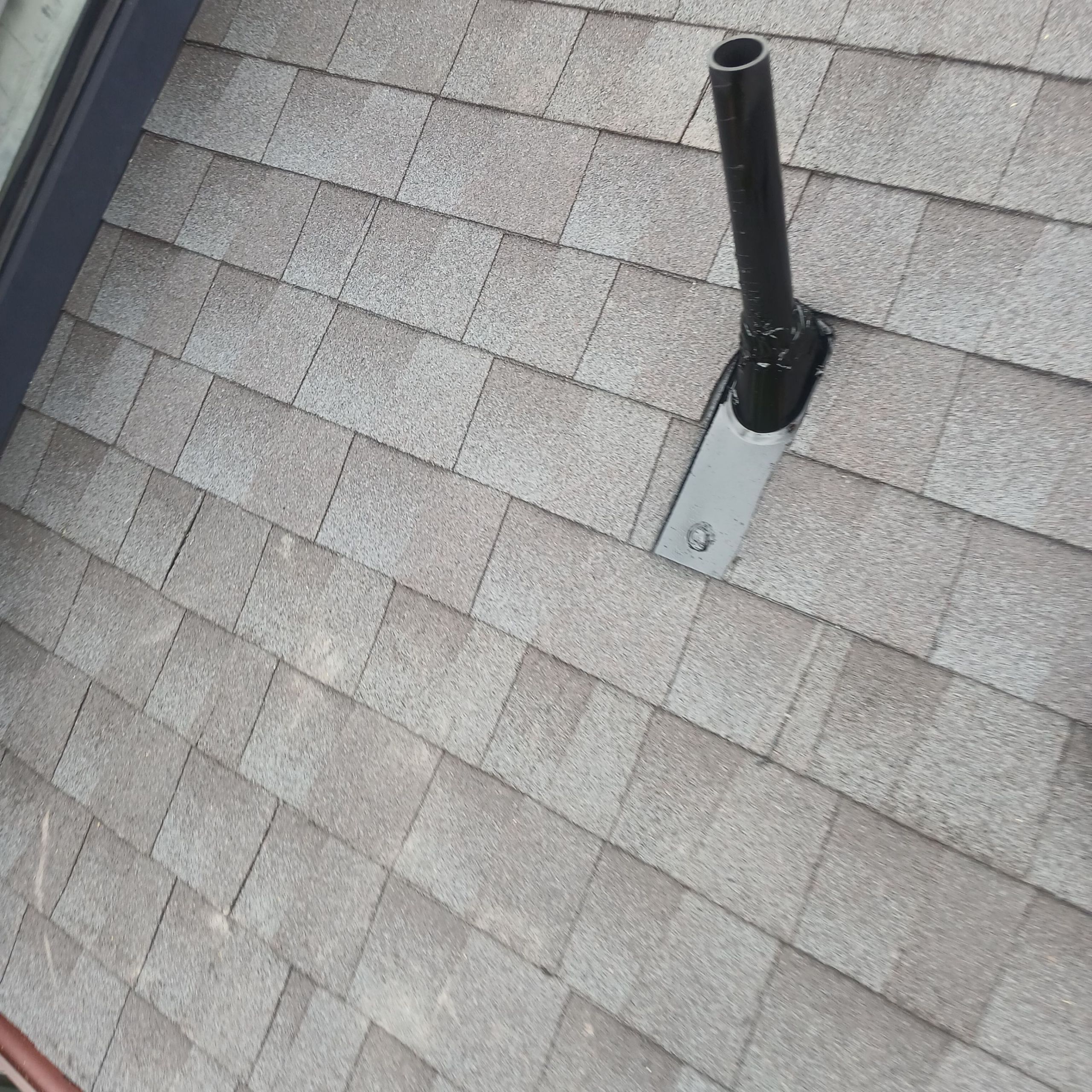 Gray shingled roof with black vent pipe.