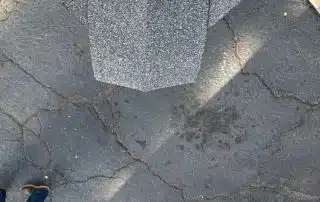 Gray roof shingles overlapping on pavement.