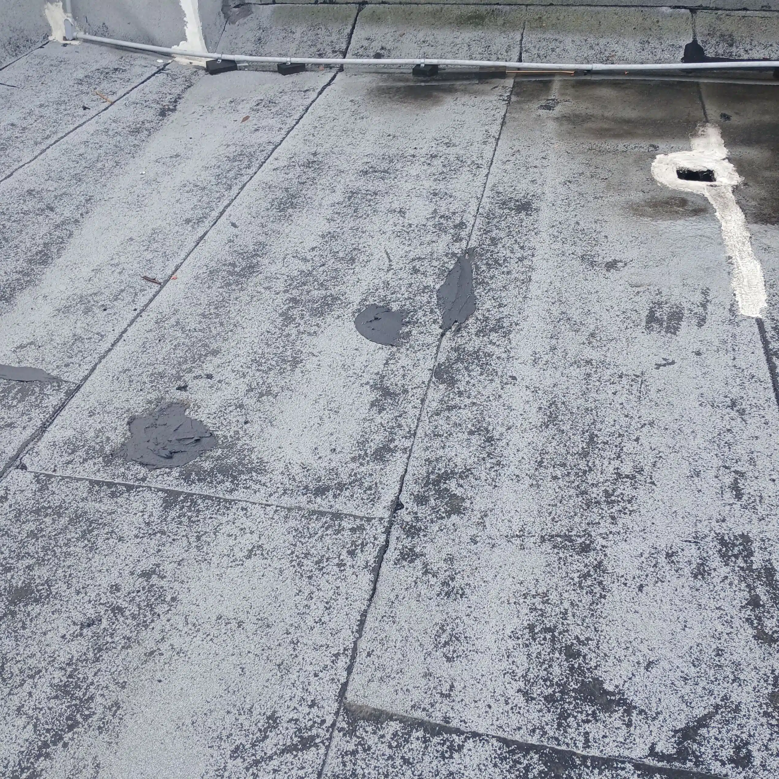 Flat roof with patched areas.