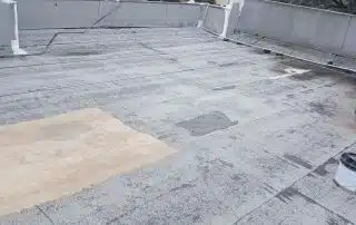 Flat roof with repair patches and trees visible.