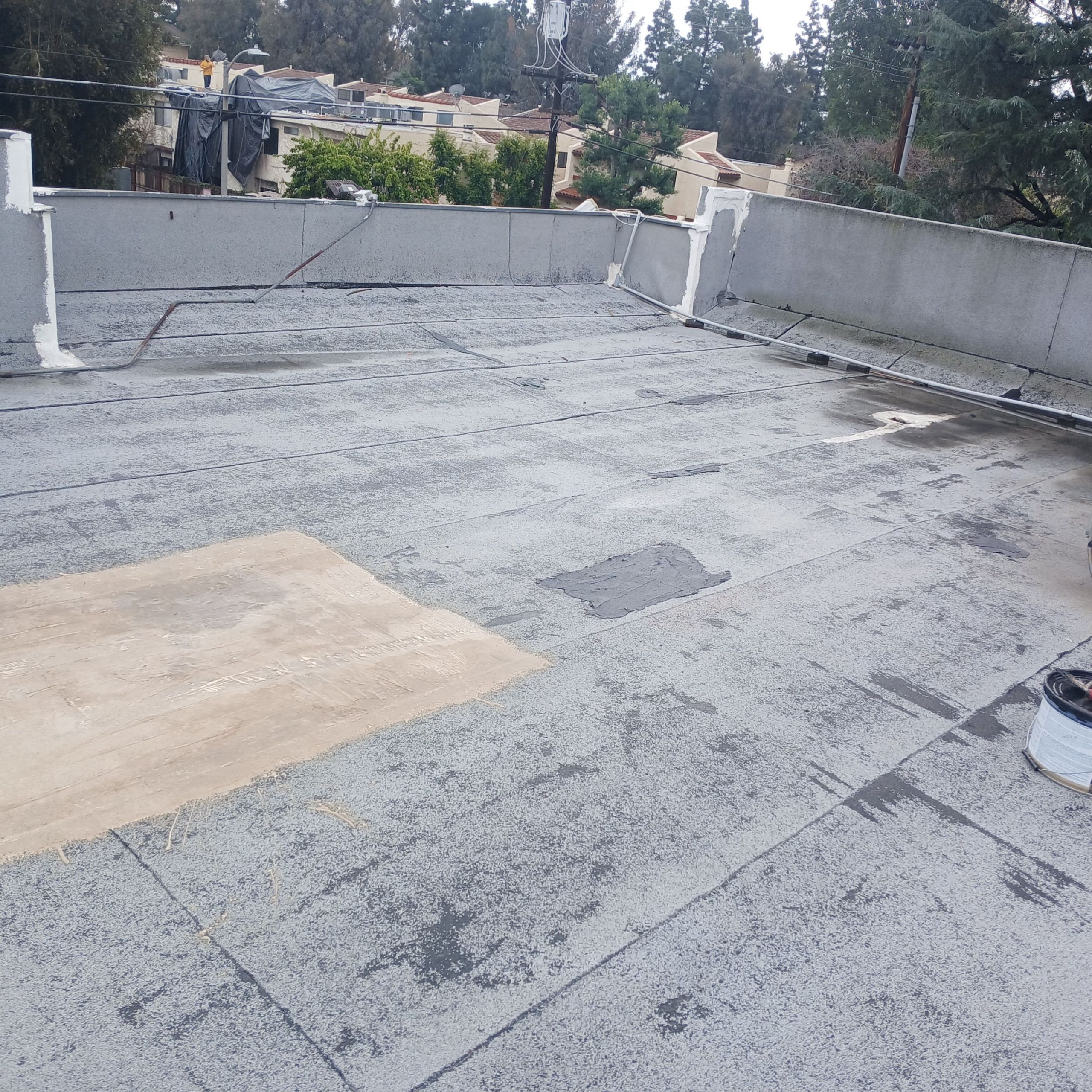 Flat roof with repair patches and trees visible.