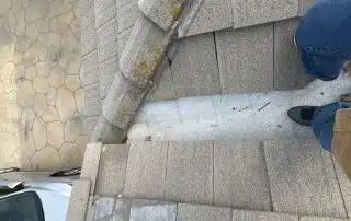 Person standing on roof edge, near driveway.