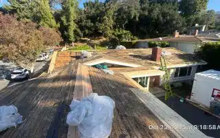 House roof under renovation with ladders and materials.