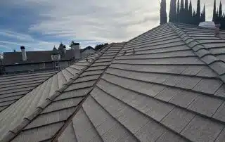 Gray roof under cloudy sky with sun and trees
