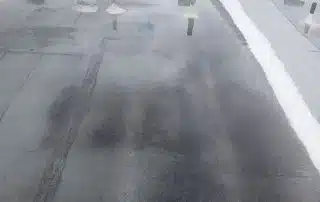 Rooftop with water puddles indicating drainage issues.