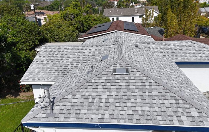 Aerial view of shingled residential rooftops with solar panels