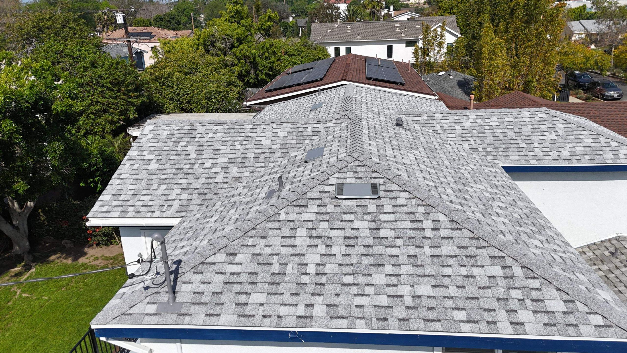 Aerial view of shingled residential rooftops with solar panels