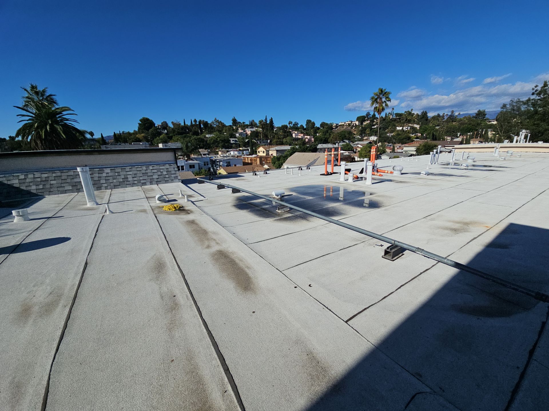 Flat rooftop with vents overlooking hillside neighborhood