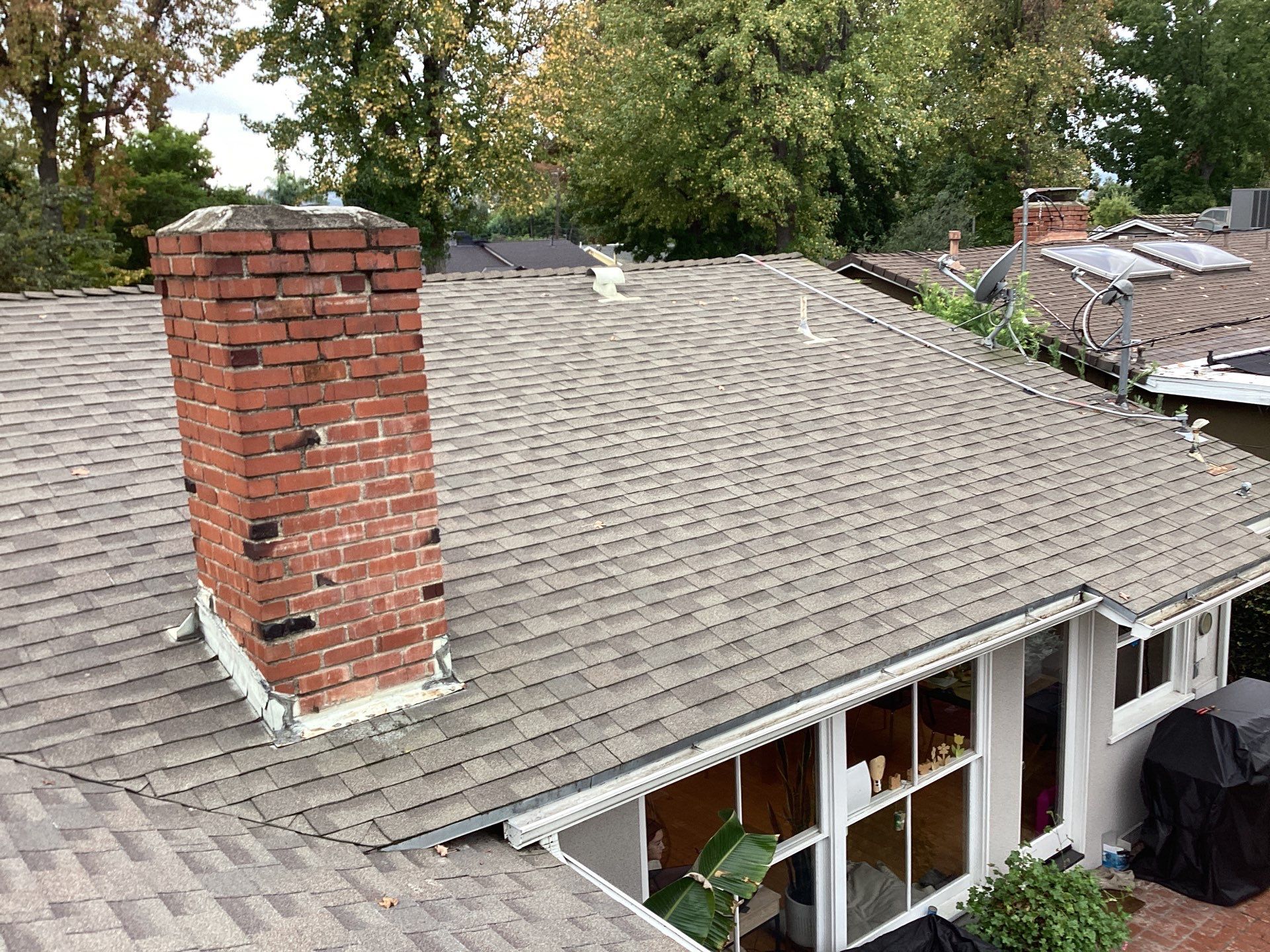 Shingled house roof with brick chimney and gutters