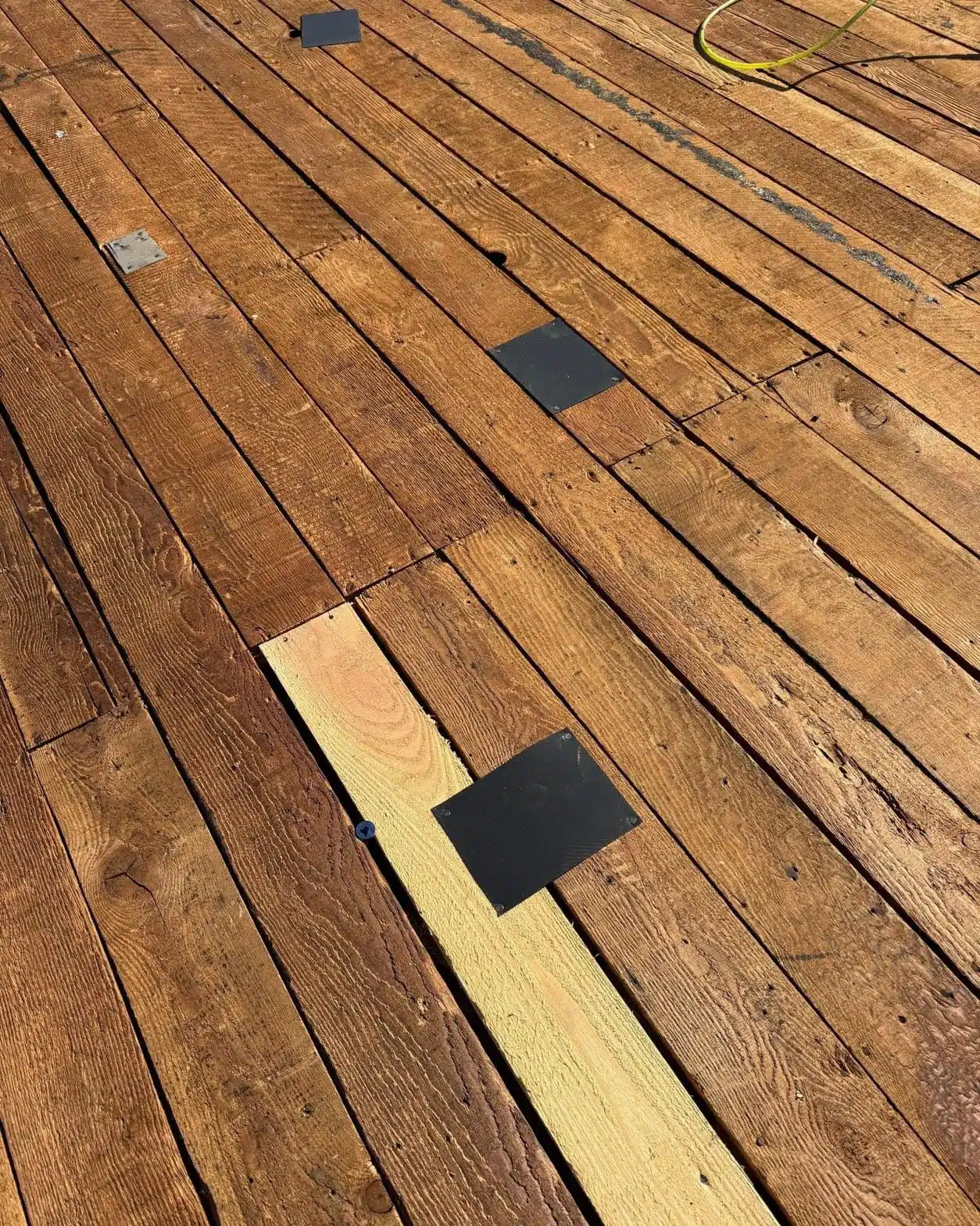 Fresh wood plank replacing a rotted board on a flat roof deck during torch-down membrane replacement in LA County